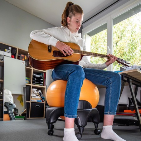Jeune fille assise sur la Tonic Chair Originale Orange entrain de jouer de la guitare 