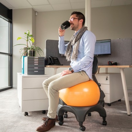 Stéphane entrain de boire un café assis sur la Tonic Chair® Confort Orange